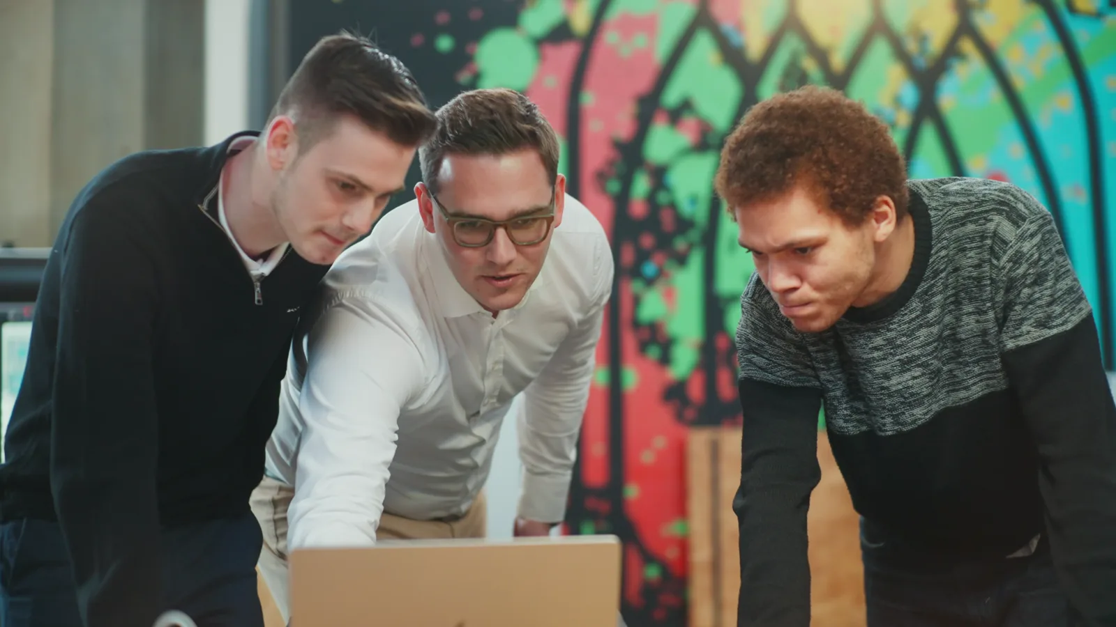 aixsolution-Team analysiert gemeinsam Daten am Laptop